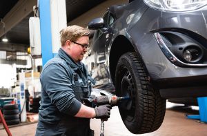 Werkstatt Mitarbeiter, der grade an einem Reifen schraubt